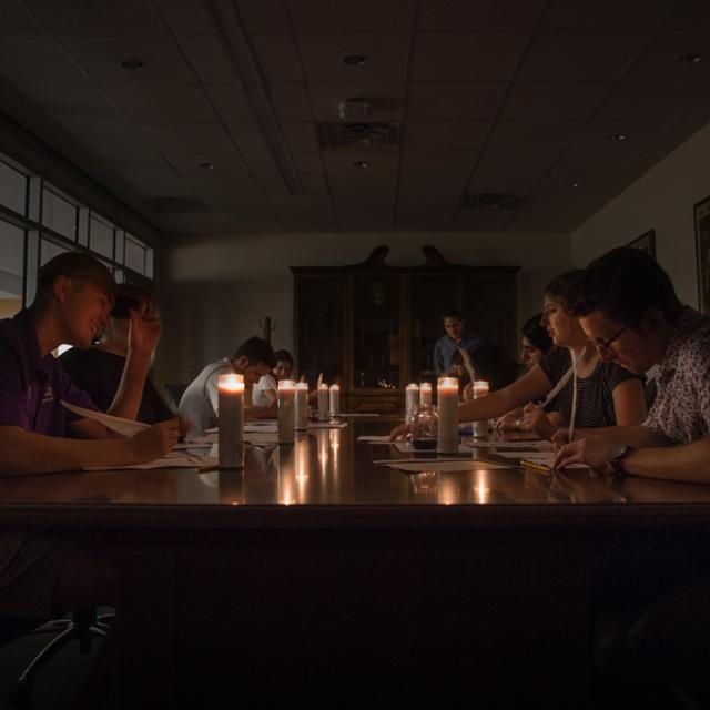 Students write with ink by candlelight 
