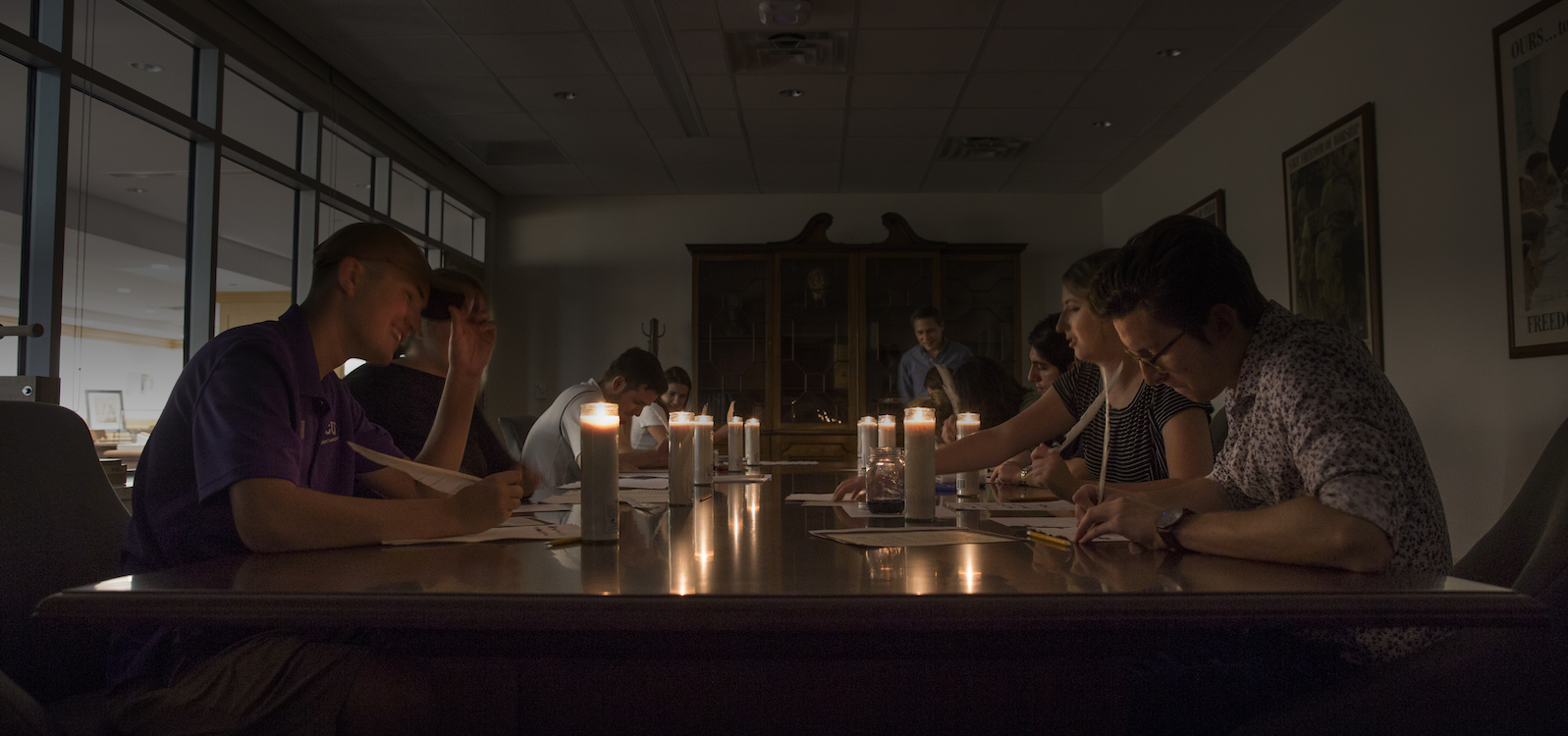 Students write with a quill and ink by candlelight 