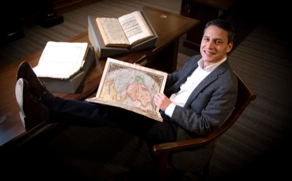 Alex Hidalgo, Ph.D., sitting with the TCU Special Collection texts