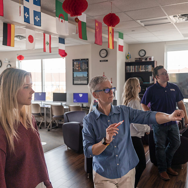 In a photograph, Muriel Cormican, Ph.D., instructs three students in German in the Center for Languages and Cultures in TCU's Scharbauer Hall.