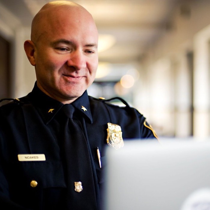 A student in a police uniform works on a laptop