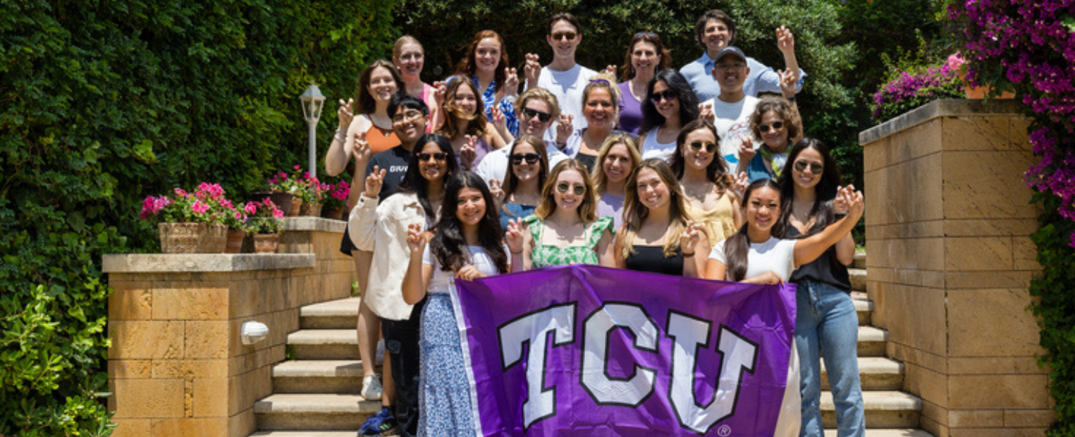 TCU students doing the 'Go Frogs' hand sign and holding a purple TCU flag in Sicily.