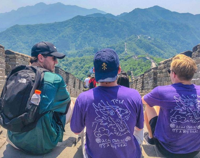 Three students sitting on Great Wall of China.