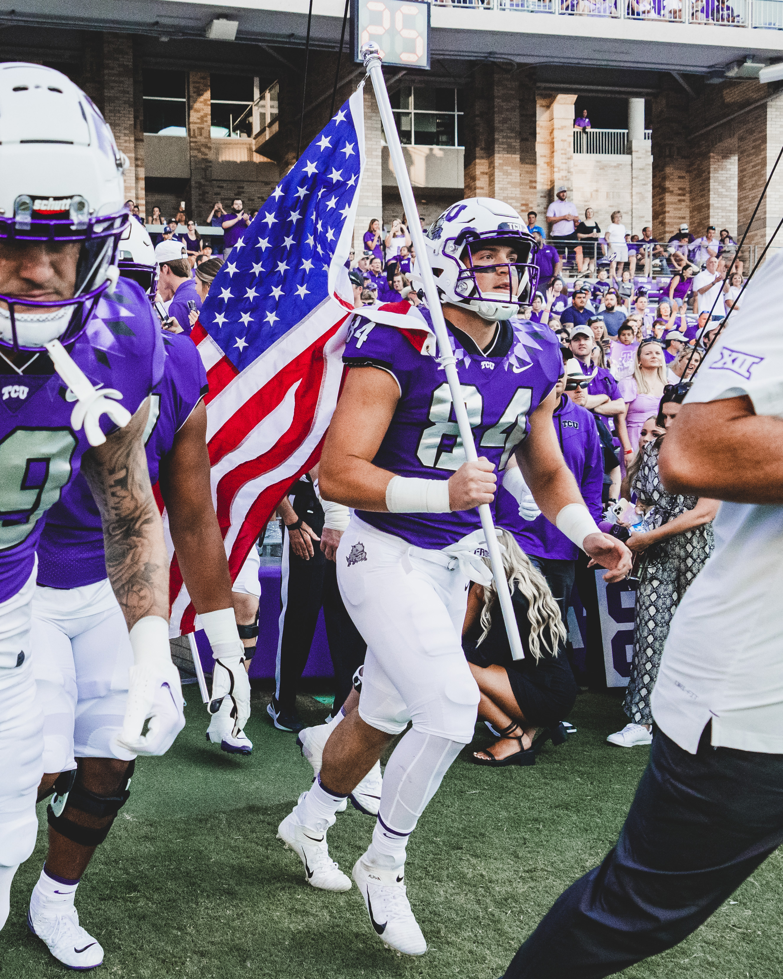 Dominic DiNunzio running onto football field with American flag.