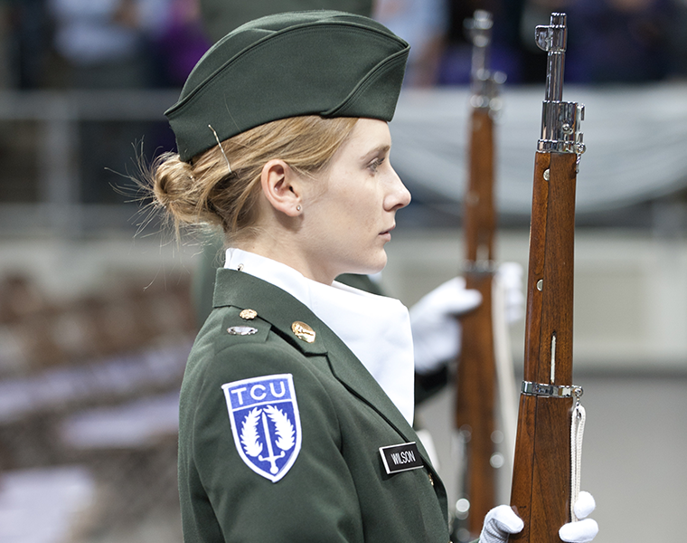 A female TCU Army ROTC cadet stands at attention during commencement. 