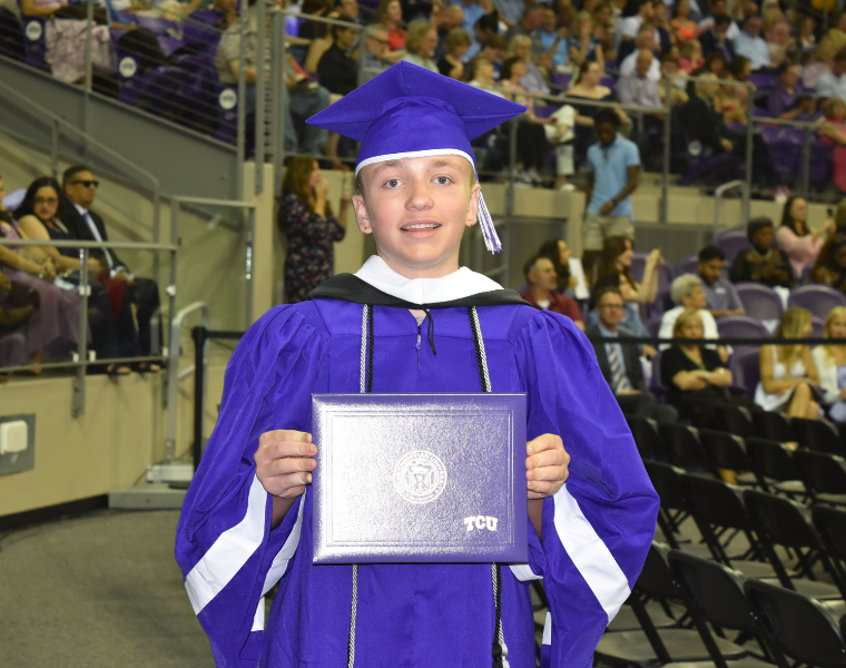 Andrew Stewart holding his diploma after walking the stage at 13 years old.