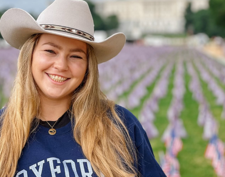 Photo of Claire Astrid Fuchs wearing a cowboy hat and an Oxford University sweatshirt.