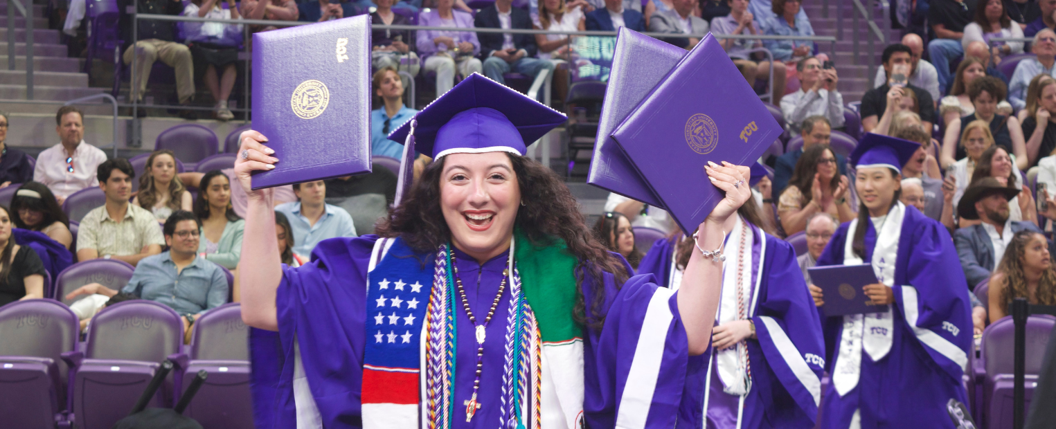 AddRan Dean Sonja Watson hands a diploma to a smiling Karina Torres wearing a purple cap and gown adorned with a Texas Christian University stole. They are in an indoor setting with purple seats in the background.