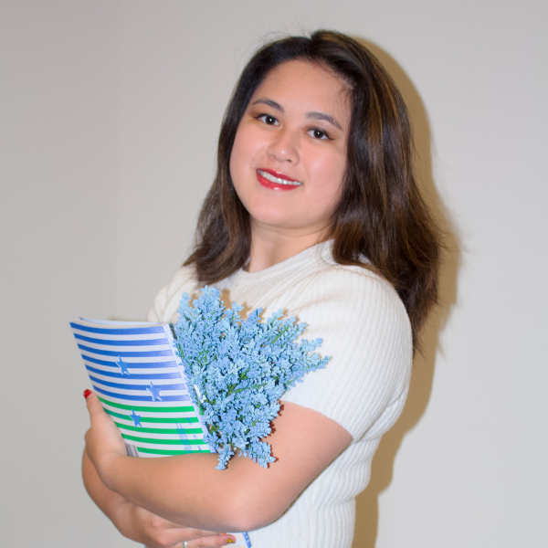 TCU student Kristy Tom holds a book and flowers.