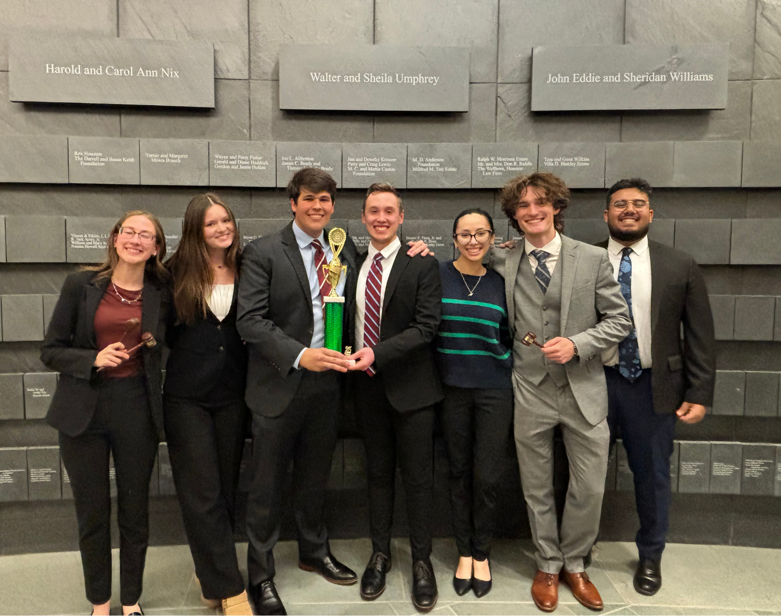 TCU Mock Trial A-Team holding their team trophy and smiling for a picture.