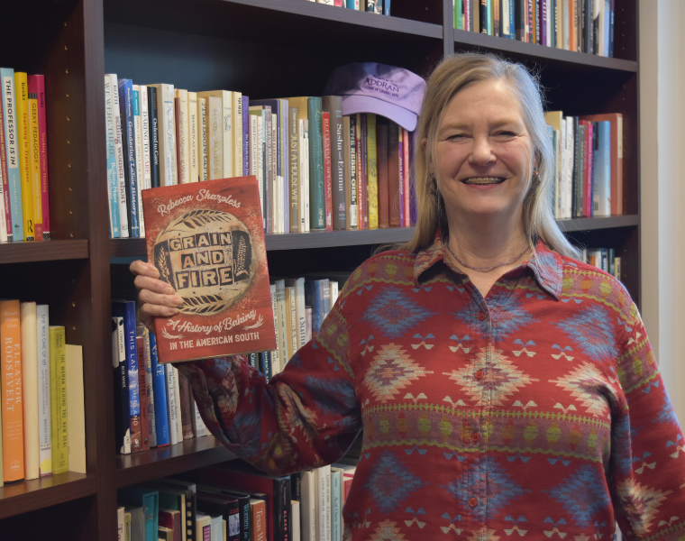 Rebecca Sharpless smiling and holding up her book 