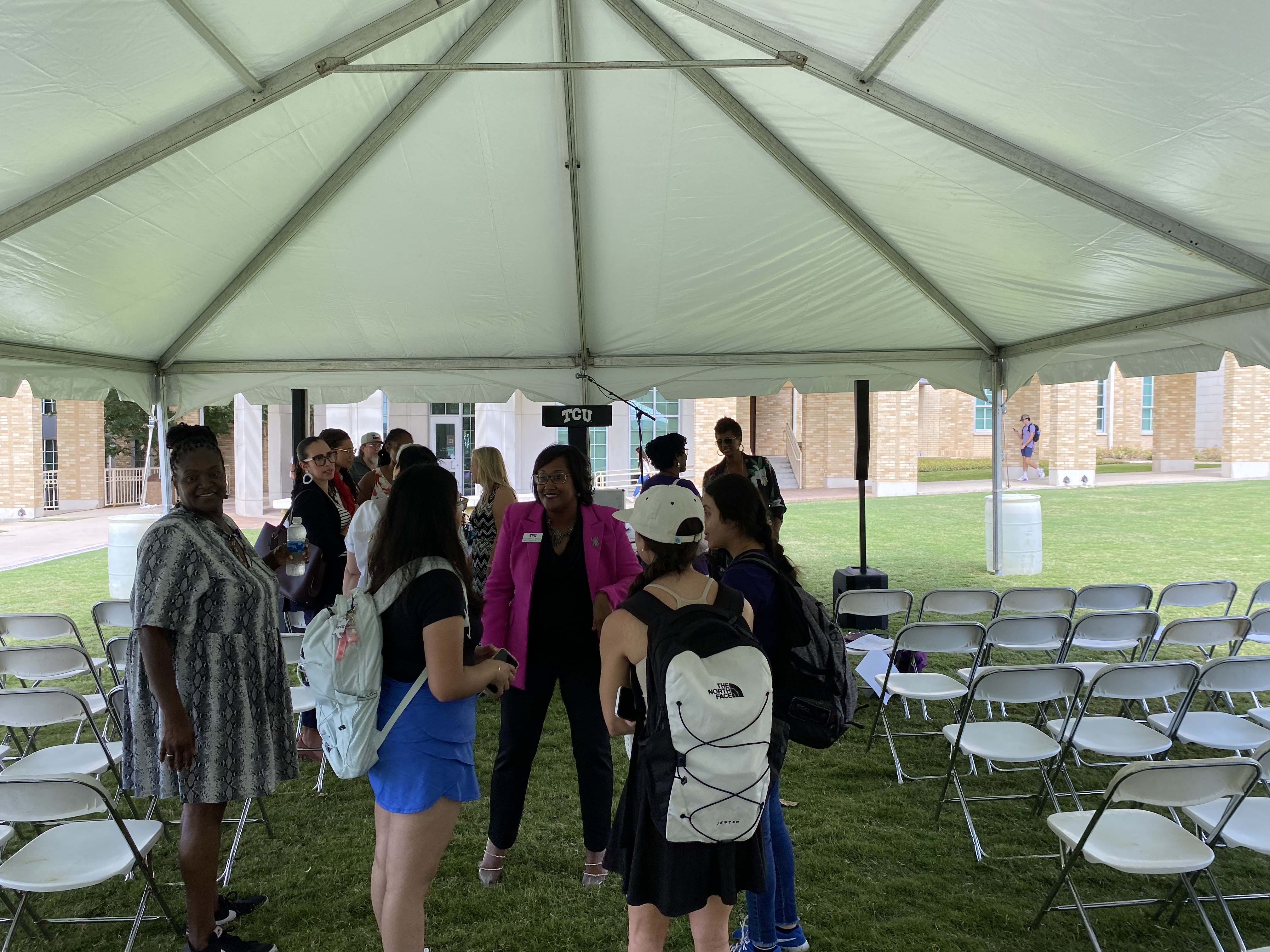 People gathered under tent in community commons.