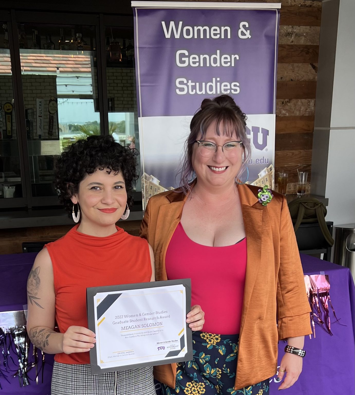 Two people standing together and posing with a certificate.