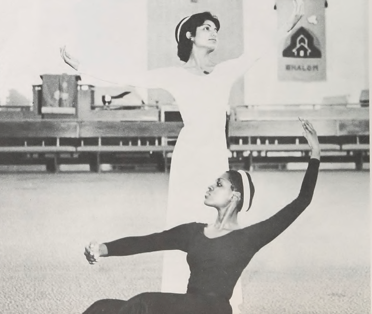 Two dancers posing. One is sitting and one is standing.